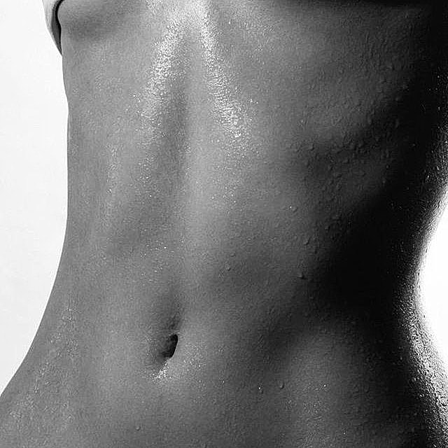 Smiling person in black swimwear against white background.