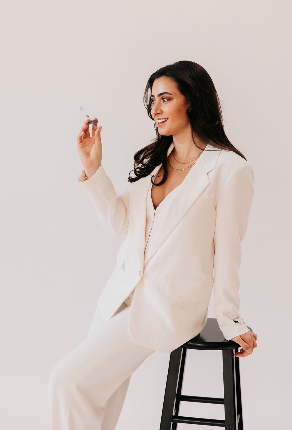 Woman in white blazer smiling against light background