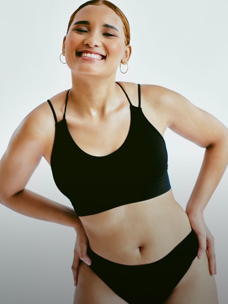 Smiling person in black swimwear against white background.