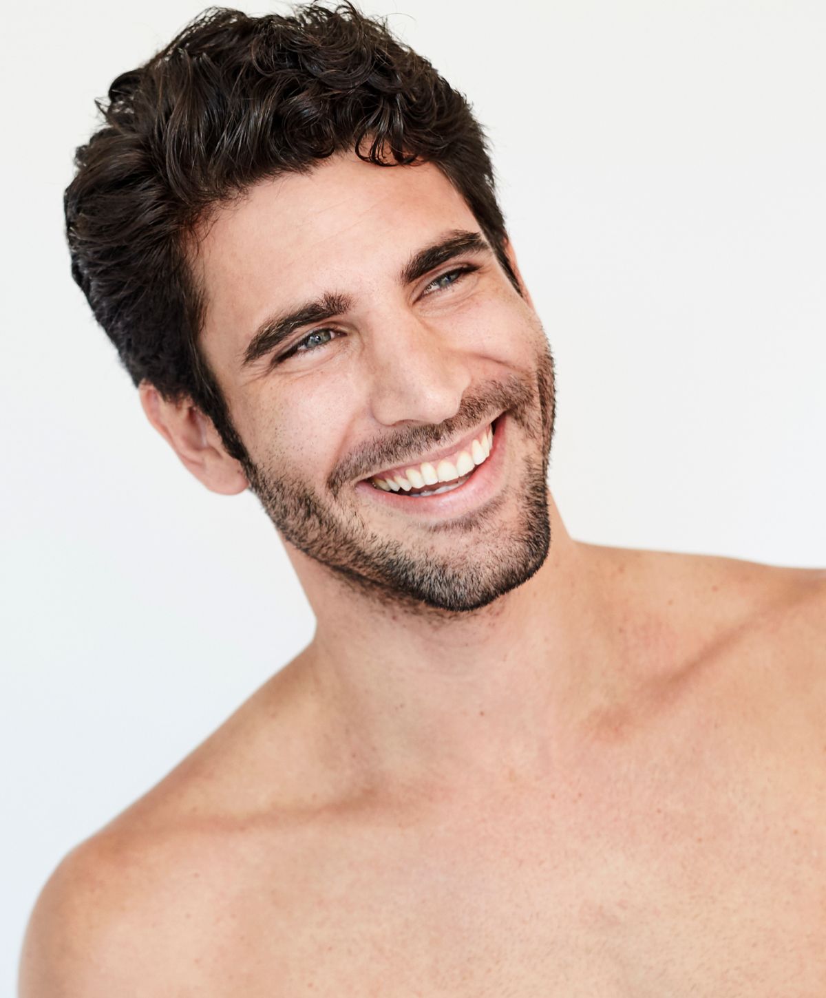 Smiling man with short, curly dark hair.