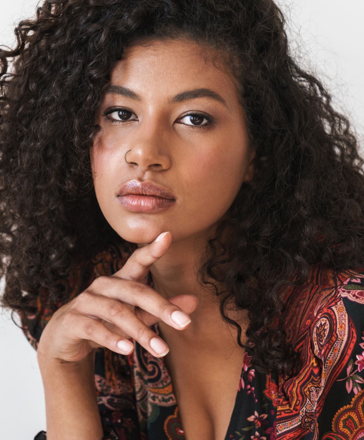 Woman with curly hair and thoughtful expression.