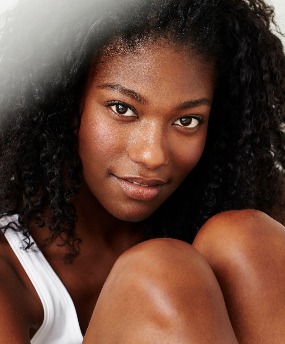 Smiling woman with curly hair and radiant skin.