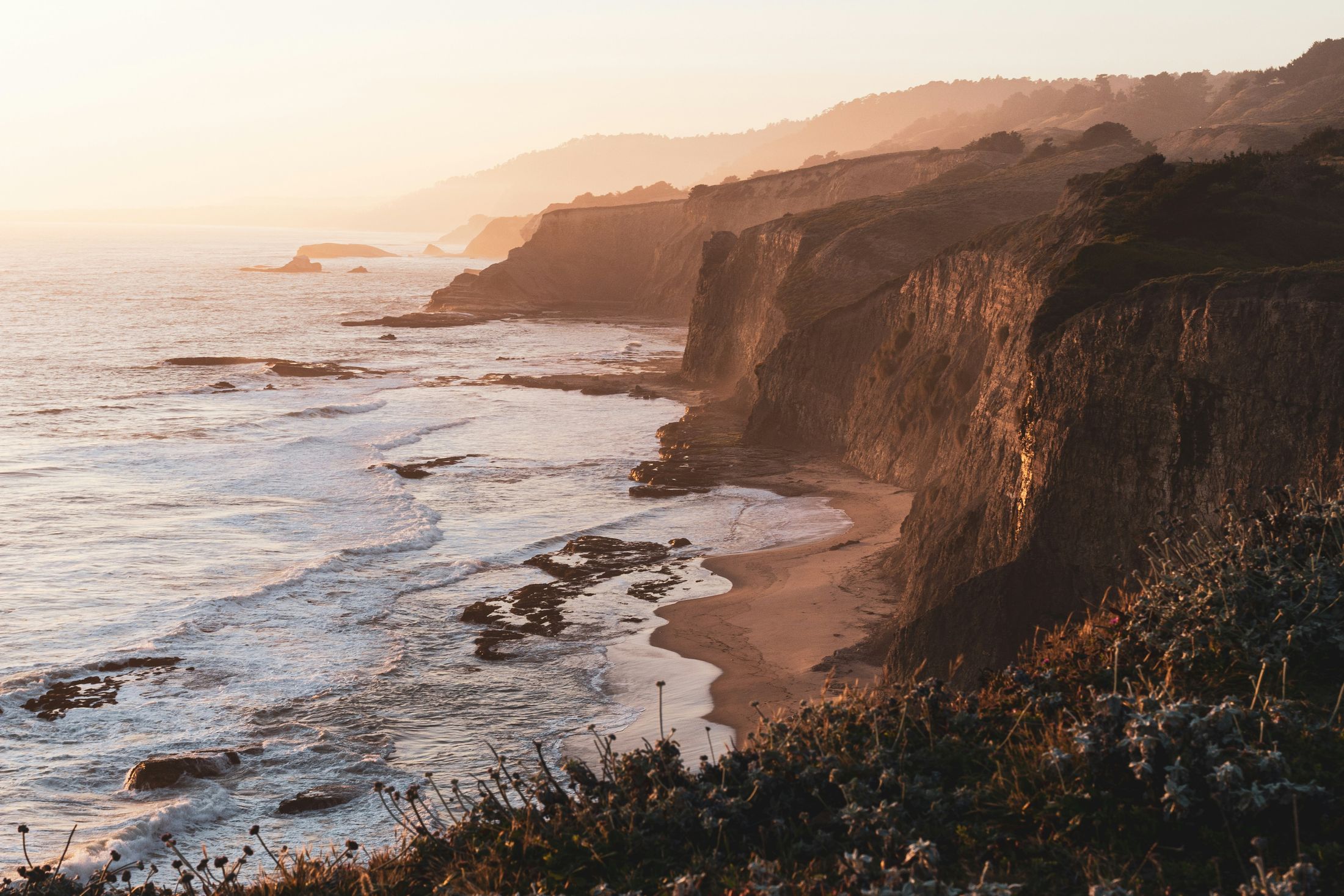 Sunlit cliffs overlooking gentle ocean waves.