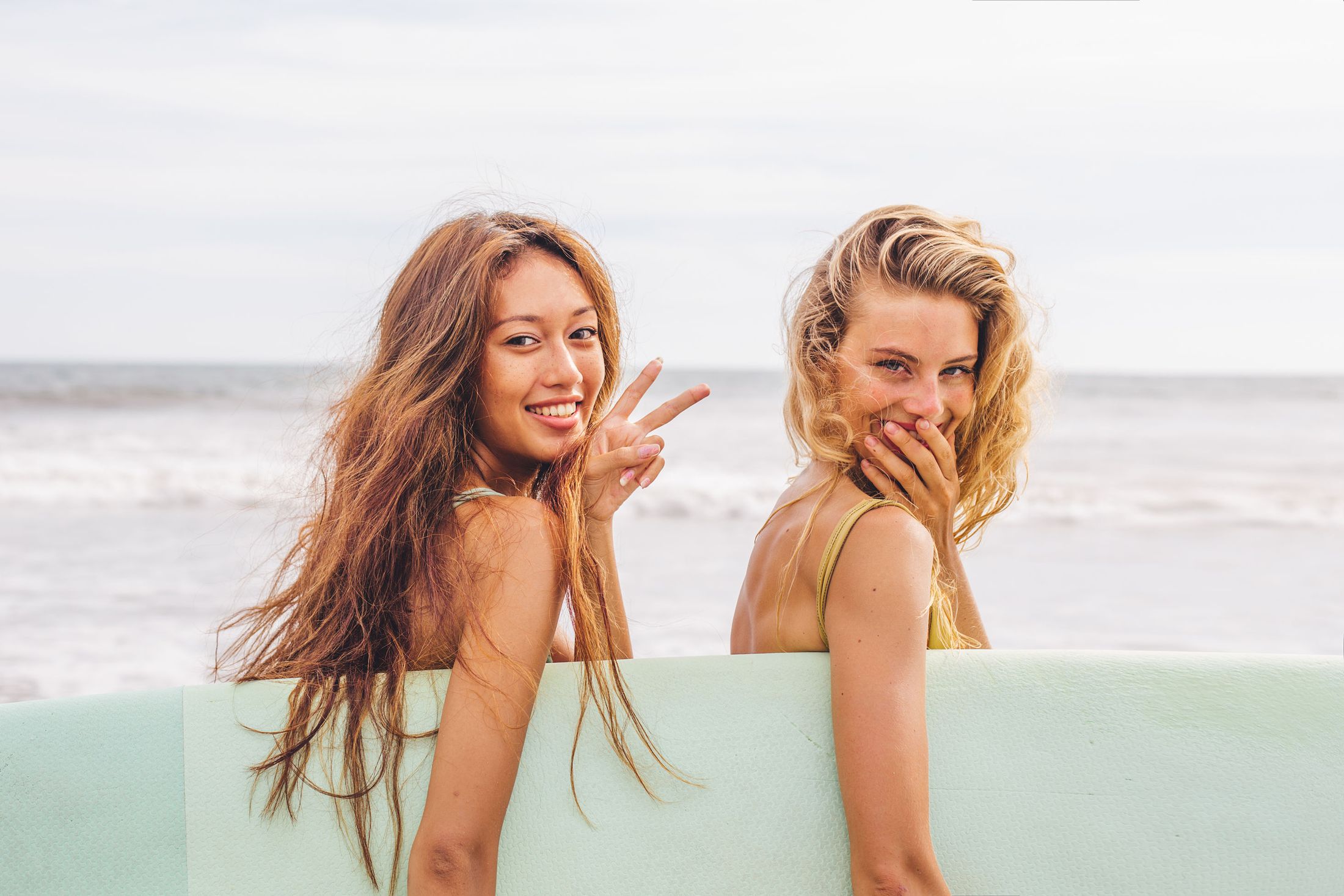 Two friends enjoying a beach day with surfboard.