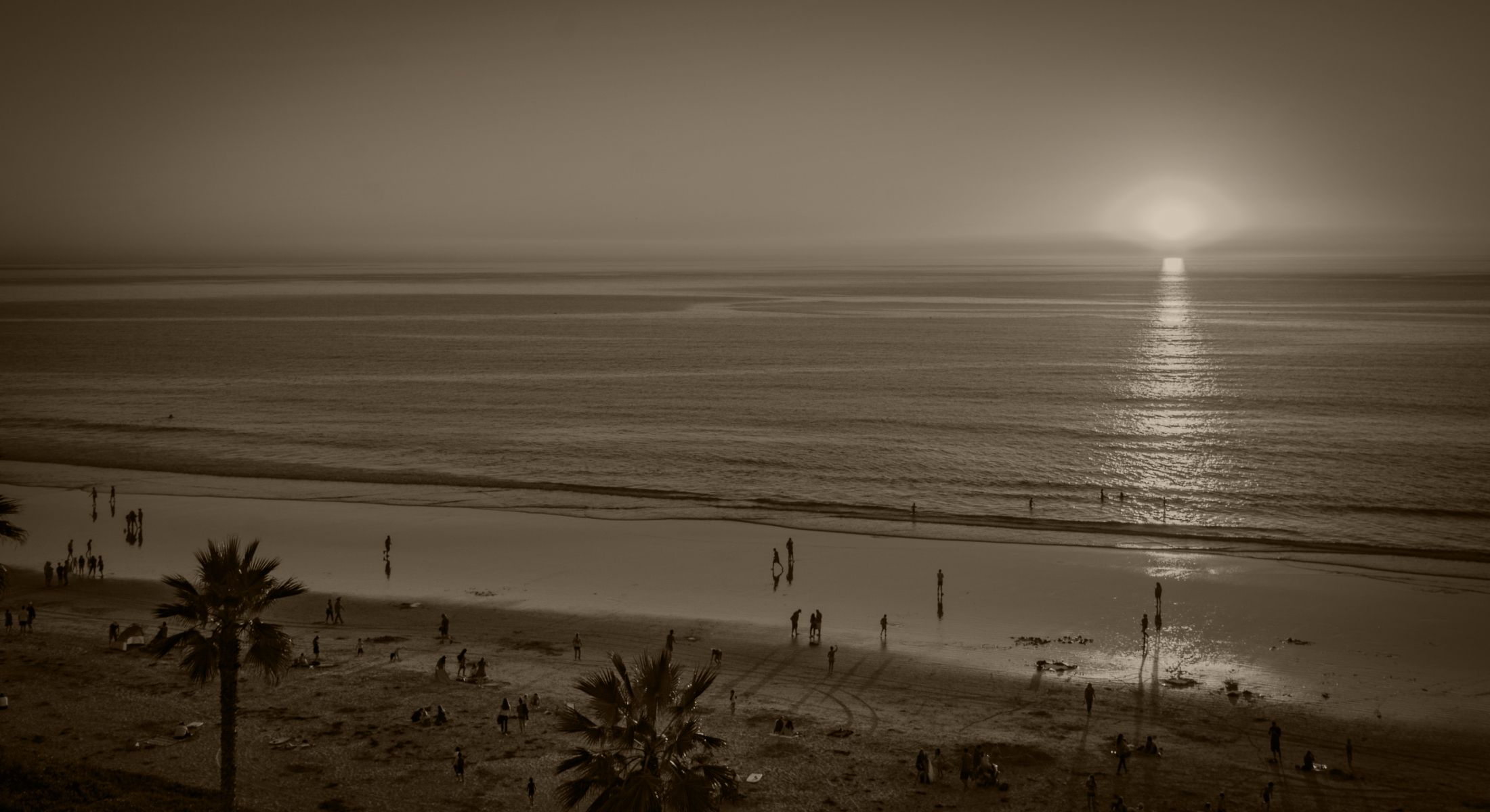 Beach sunset with silhouettes of people.