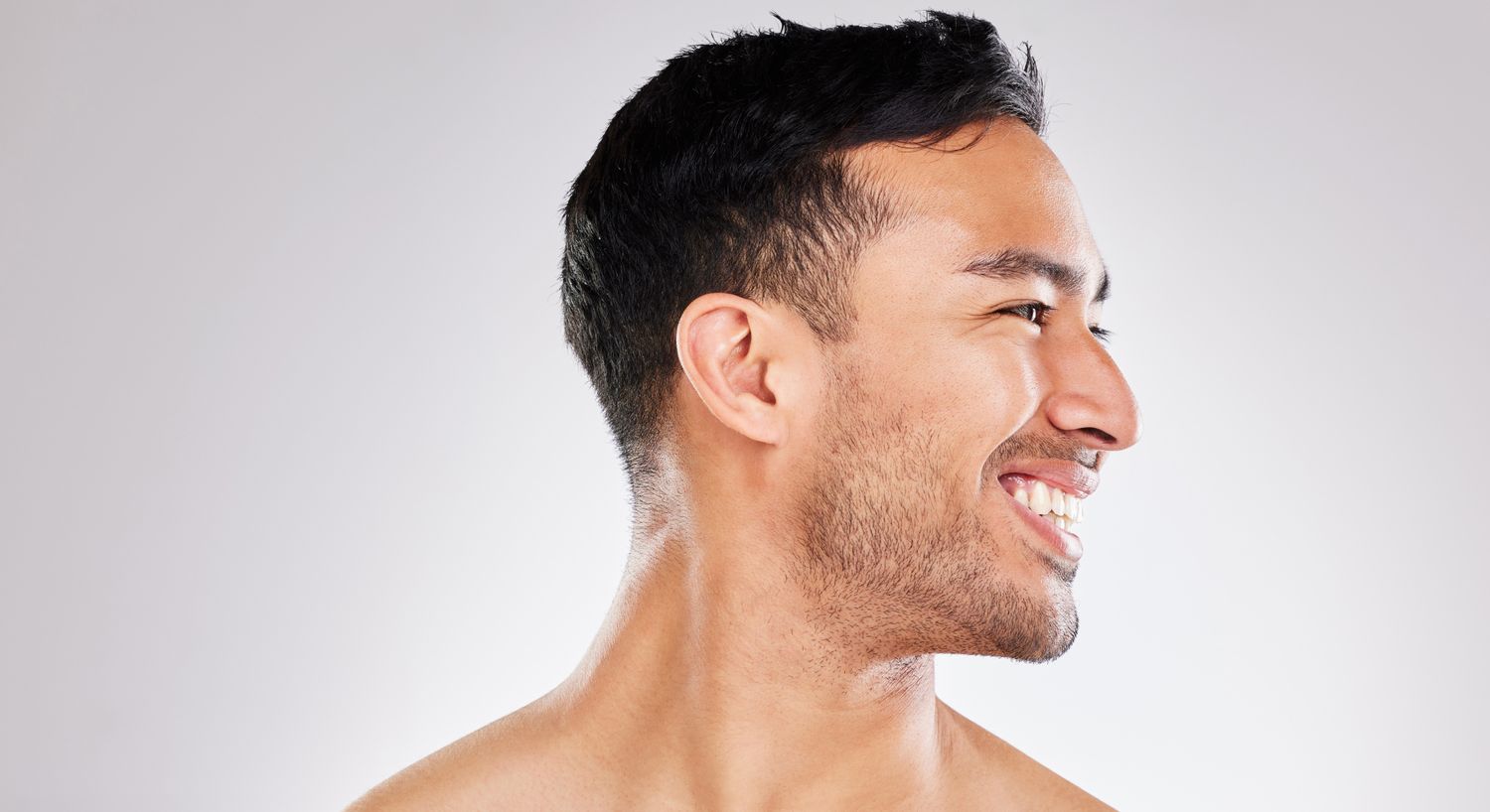 Profile of a smiling man against plain background