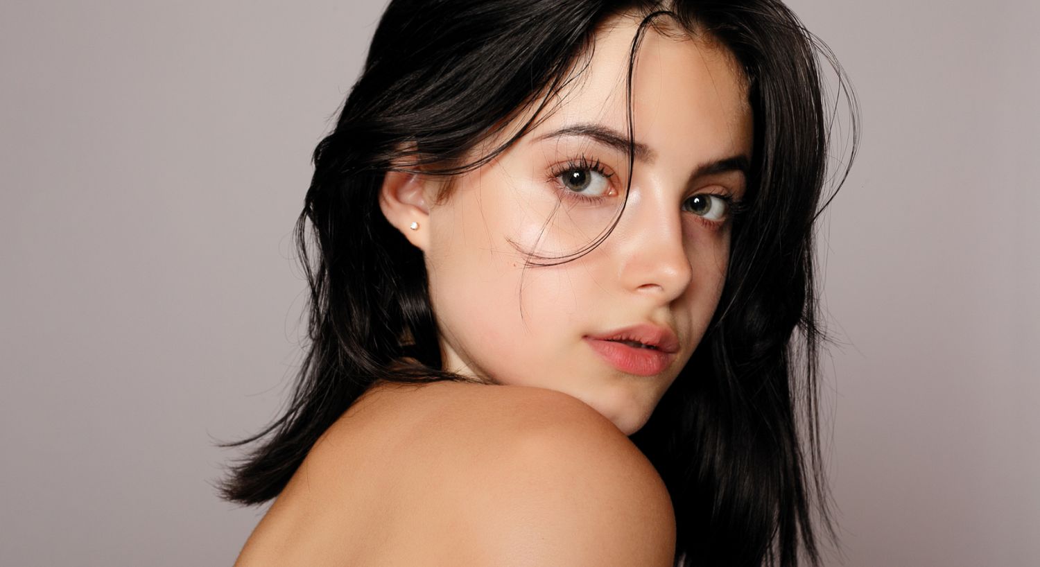 Young woman with flowing dark hair, soft expression.